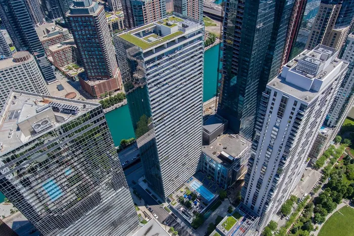 Aerial view of tall modern skyscrapers with glass facades, rooftop greenery, and a river running through an urban cityscape.