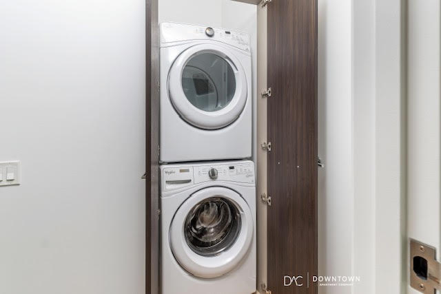 Stacked front-loading washer and dryer units are enclosed in a closet with dark wood doors, located in a modern laundry area.