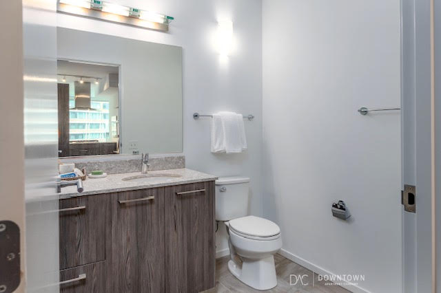 Modern bathroom with a large mirror, single sink vanity, toilet, towel rack, and wall-mounted light fixture above the mirror.