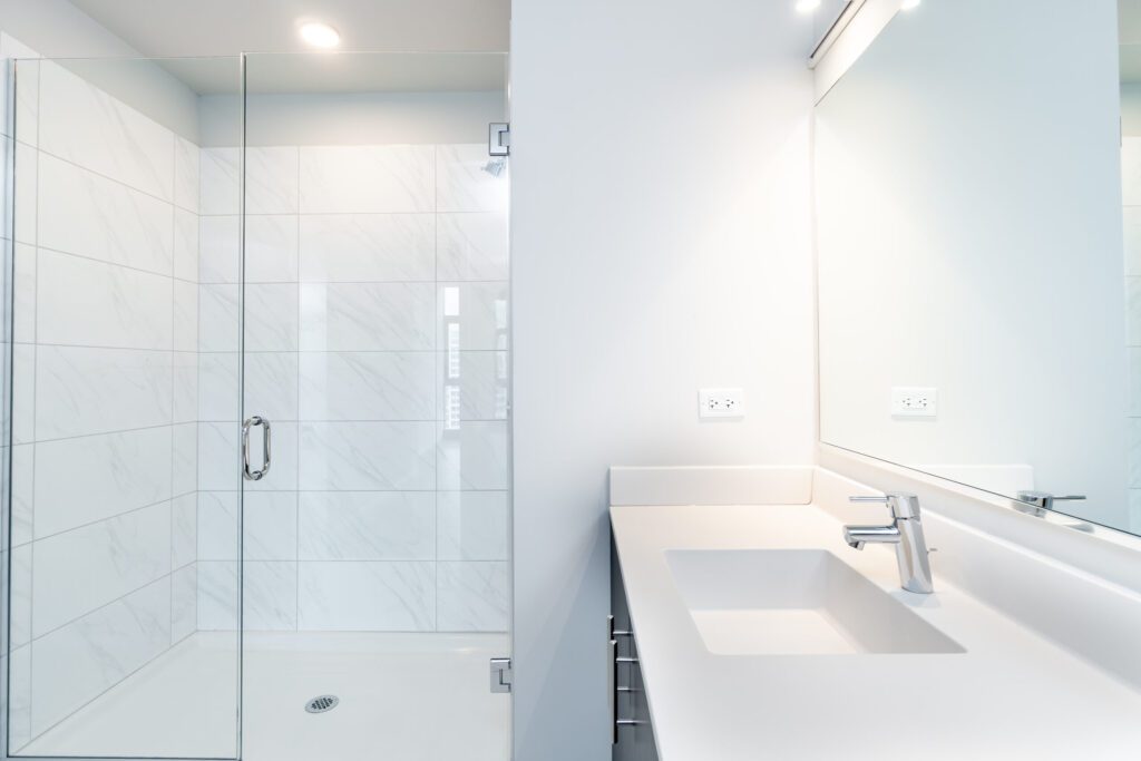 Modern bathroom with a glass-enclosed shower and a white countertop with an integrated sink and faucet.
