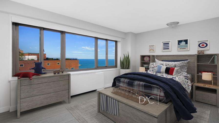 Modern bedroom with a twin bed, wooden furniture, nautical-themed decor, large window, and an ocean view outside.