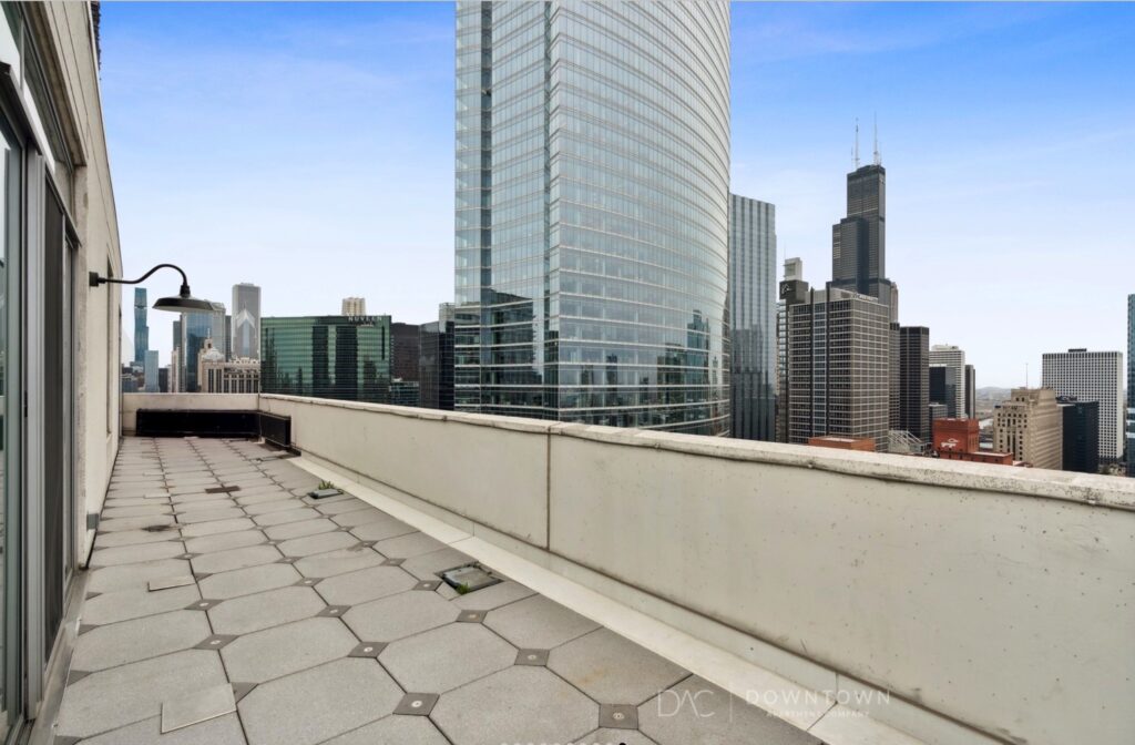 Rooftop terrace with hexagonal tiles and city skyline views featuring tall, modern skyscrapers under a clear sky.