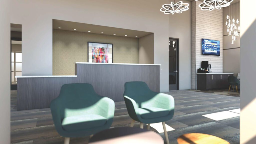 Modern lobby with two teal chairs, a reception desk with overhead lighting, artwork on the wall, and a TV. A coffee machine sits on a side counter.
