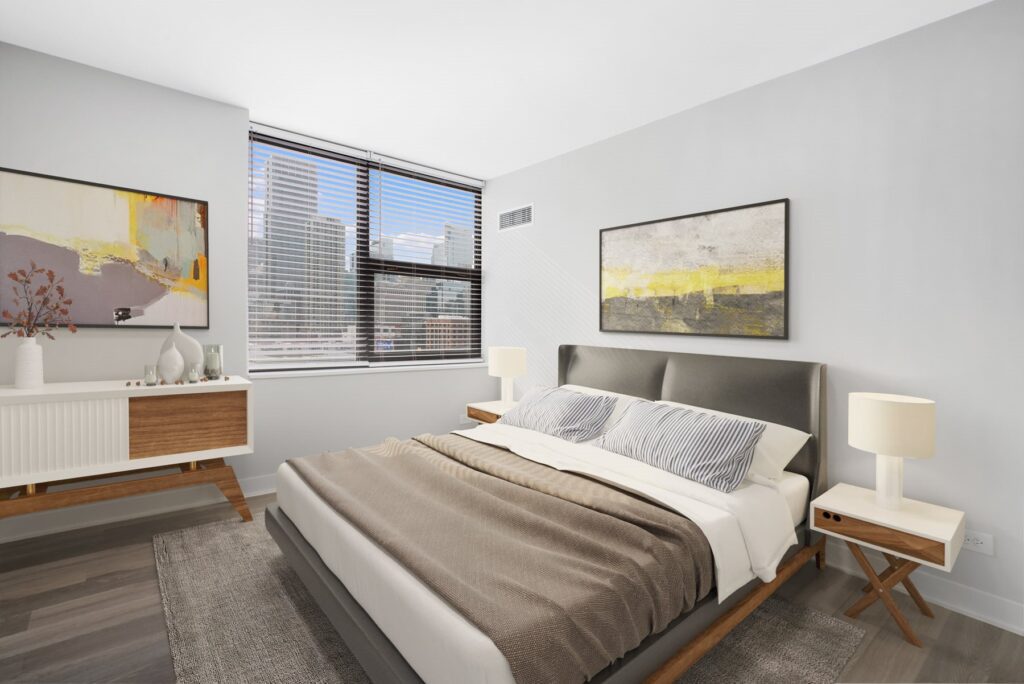 Modern bedroom with a large bed, two nightstands with lamps, abstract art on walls, a sideboard, and a window showing a cityscape.