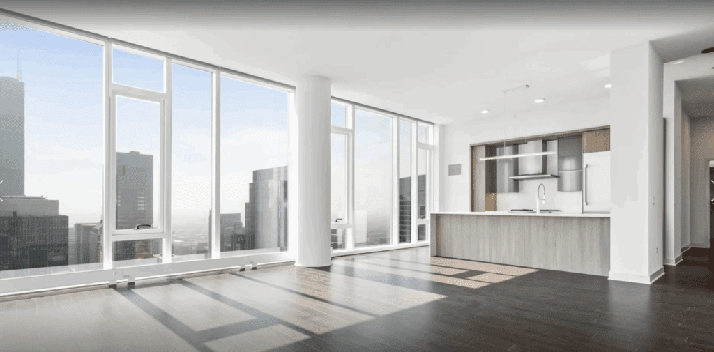 Modern high-rise apartment with floor-to-ceiling windows, city views, dark wood flooring, and an open kitchen with white and wood cabinetry.
