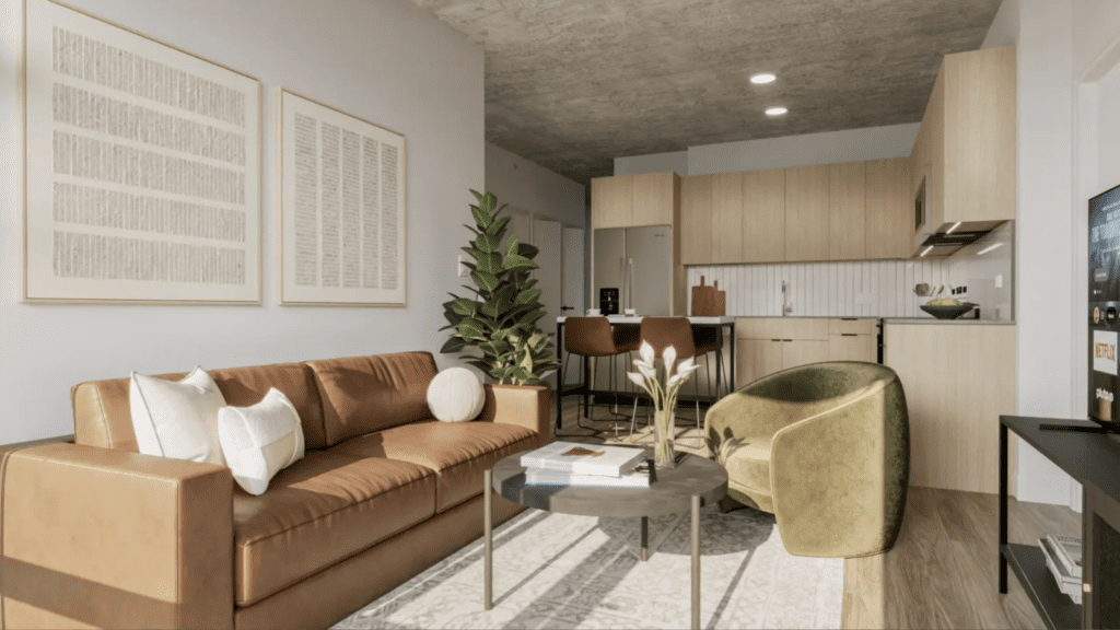 Modern living room with a brown leather sofa, green armchair, coffee table, potted plants, and an open kitchen with light wood cabinets in the background.