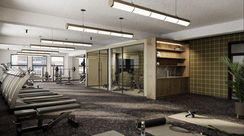 Modern gym with treadmills, weights, a glass-enclosed room, fitness equipment, and a kitchenette area with shelves. Large windows provide natural light.