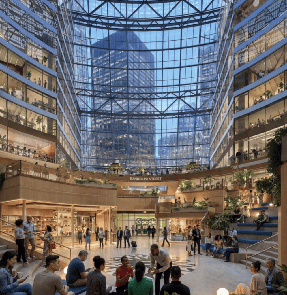 People sit and walk in a spacious indoor atrium with glass ceiling and multiple floors lined with offices and shops; large city buildings visible outside.
