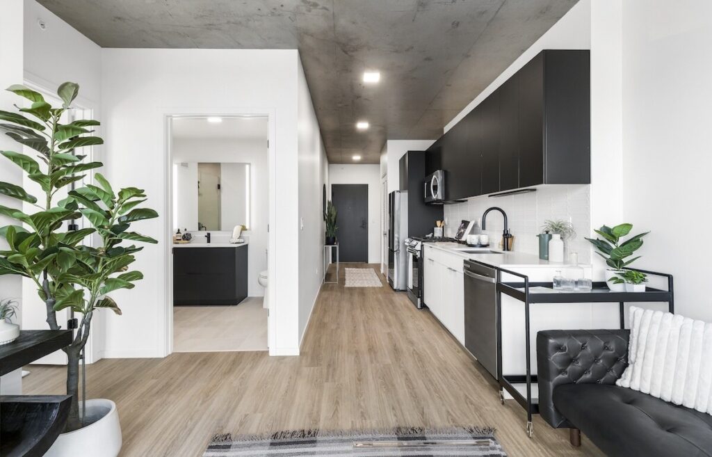 Luxury apartments at The Elizabeth by Sterling Bay. modern apartment kitchen featuring black cabinets, stainless steel appliances, white countertops, and a view into a bathroom through a doorway.